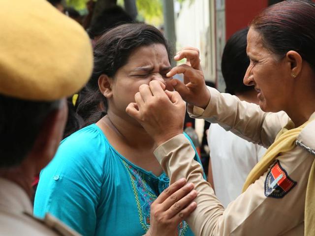 An aspirant of NEET-2 writhes in pain as a police woman assists her in removing her nose pin, an item not allowed inside the examination centre in Jaipur, Rajasthan on Sunday. (Himanshu Vyas/ Hindustan Times)
