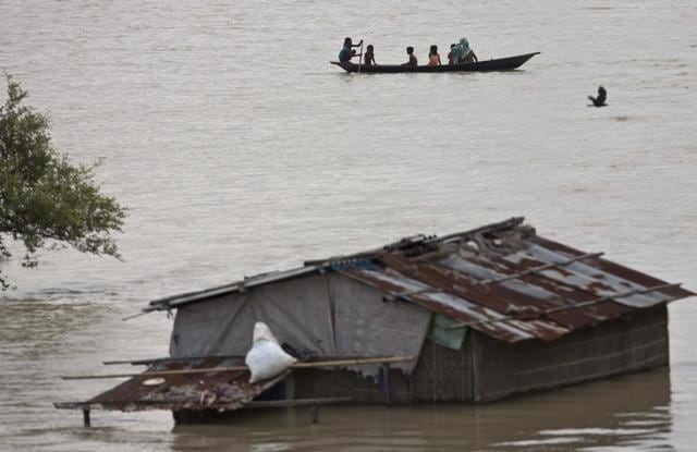 An family moves on a boat after heavy monsoon rains flooded Burhaburhi village, east of Guwahati. (PTI Photo) An family moves on a boat after heavy monsoon rains flooded Burhaburhi village, east of Guwahati. (PTI Photo)