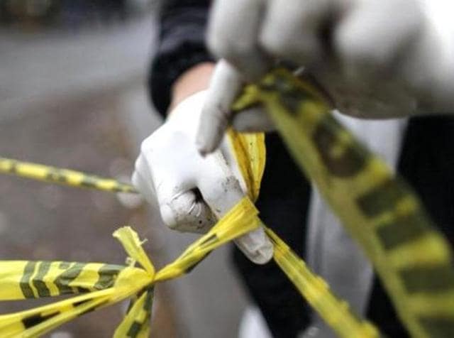 A forensic technician ties a police line together to seal off a crime scene. (Reuters File Photo) A forensic technician ties a police line together to seal off a crime scene. (Reuters File Photo)