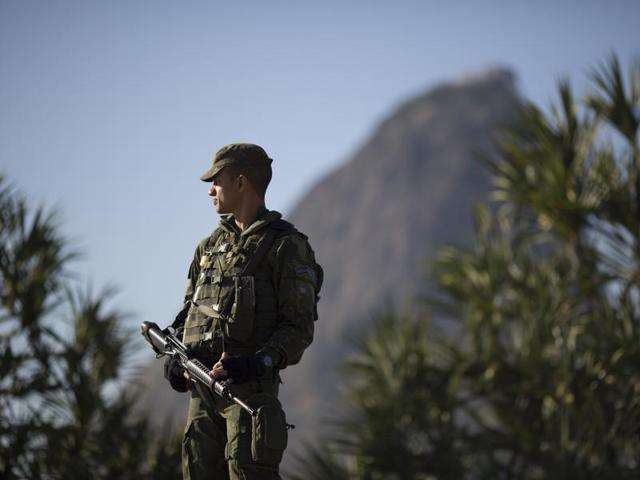 With Sugar Loaf mountain in the background a soldier patrols near Botafogo beach in Rio de Janeiro, Brazil. (AP Photo)