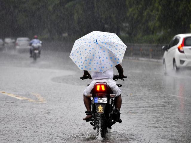 A man drives a motocycle as rains lashed across Noida. (Sunil Ghosh /HT Photo)