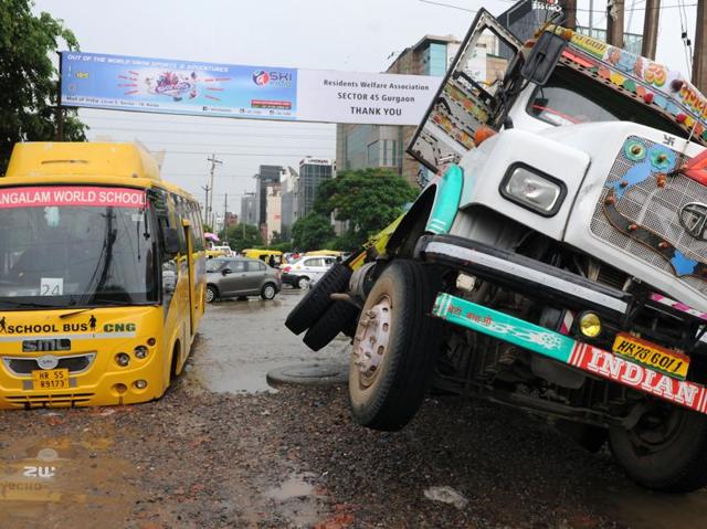 KR Mangalam World School bus and a loaded truck with building construction material were stuck as a road caved in due to heavy rains, in Gurgaon. (Parveen Kumar/HT Photo)