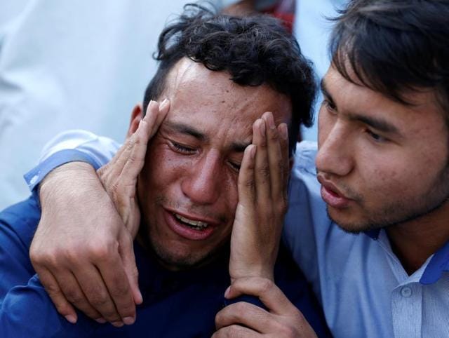 Relatives and friends inspect shoes and other belongings of those who were killed in the twin suicide attack, gathered on the ground at a mosque in Kabul.(AFP Photo)