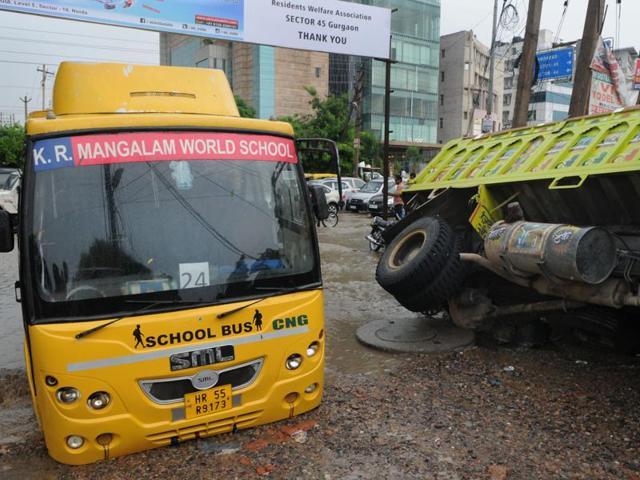 A school bus of KR Mangalam World School and a truck loaded with construction material stuck in gravel after a road caved in at sector 45. (Parveen Kumar/HT Photo) A school bus of KR Mangalam World School and a truck loaded with construction material stuck in gravel after a road caved in at sector 45. (Parveen Kumar/HT Photo)