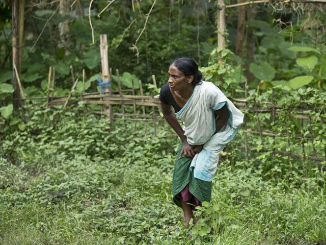 A woman watches wild elephants enter the premises of her house as animals take shelter on highlands following floods in Kaziranga National Park. (AP Photo)