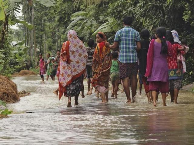 A woman (C) looks on as she walks with others to a safer place through a flooded road after incessant rains at Bullut village in Kamrup district in Assam. (Reuters)