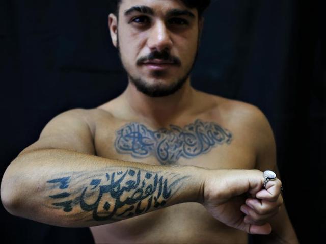 Portrait of bearded muslim man with bare chest and with tattooed hands  lying on the gray cozy bed Stock Photo | Adobe Stock