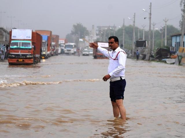 A traffic constable manages the traffic at Hero Honda Chowk on July 29, 2016, after the heavy rainfall a day earlier. The chowk was submerged in up to 4 ft due to Badshahpur drain overflowing.(Parveen Kumar / HT Photo)