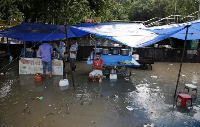 A roadside food vendor waits for customers as he sits next to his partially submerged food stall during a rainstorm in New Delhi. (AP Photo) A roadside food vendor waits for customers as he sits next to his partially submerged food stall during a rainstorm in New Delhi. (AP Photo)