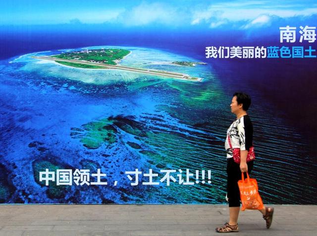A woman walks past a billboard featuring an image of an island in South China Sea on display with Chinese words that read: "South China Sea, our beautiful motherland, we won't let go an inch" in Weifang. (AP) A woman walks past a billboard featuring an image of an island in South China Sea on display with Chinese words that read: "South China Sea, our beautiful motherland, we won't let go an inch" in Weifang. (AP)
