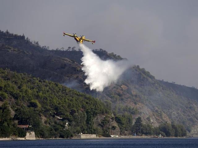 An aircraft drops water over a fire at the village of Limni on the island of Evia. (AP Photo) An aircraft drops water over a fire at the village of Limni on the island of Evia. (AP Photo)