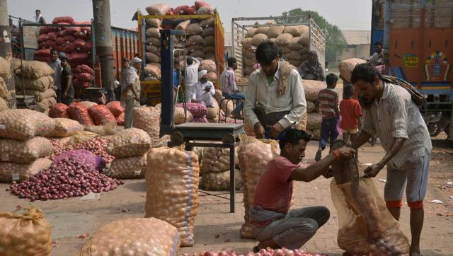 Indian labourers fill sacks with onions after sorting them at a wholesale vegetable and fruit market on the outskirts of Amritsar.(AFP)