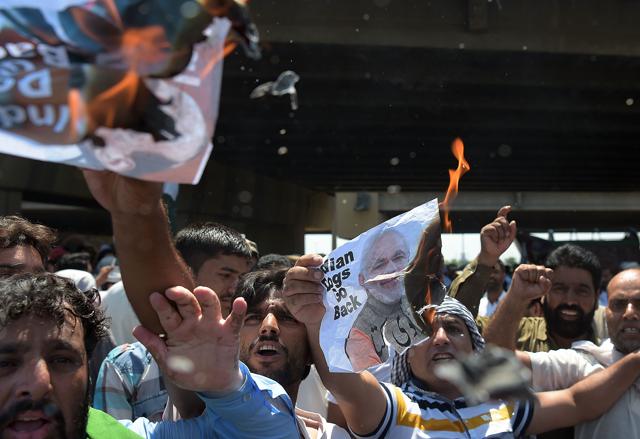 Protesters burn posters bearing the images of Indian Prime Minister Narendra Modi and RajnathSingh. (AFP)