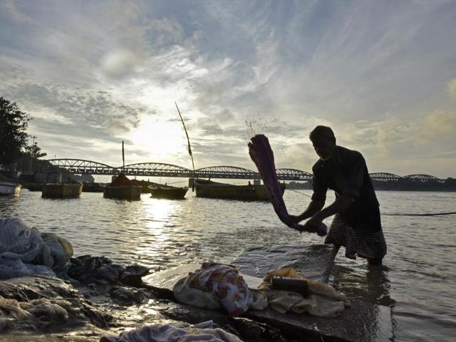 A dhobi washes clothes at Rajghat in Varanasi. 15,000 tonnes of ashes released into the river every year. (Ravi Choudhary/HT PHOTO)
