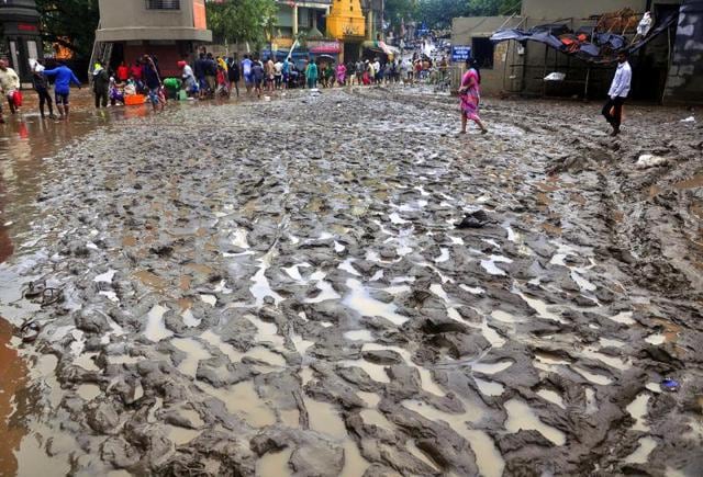 Resident makes way through muddy street after flood water recedes caused by heavy rain in Nashik, India, on Tuesday.