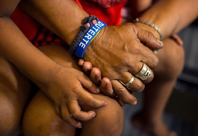 This photo taken on June 8 shows a mother wearing a “Duterte” wristband as she holds her daughter's hand after she was temporarily detained for violating a curfew in Manila. (AFP) This photo taken on June 8 shows a mother wearing a “Duterte” wristband as she holds her daughter's hand after she was temporarily detained for violating a curfew in Manila. (AFP)