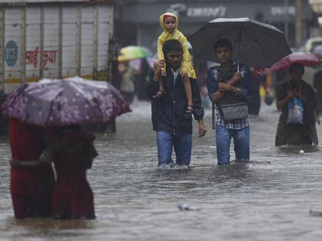 A man carries his child on his shoulder as they walk though the flooded water at sion during heavy rains in Mumbai. (Vijayanand Gupta) 