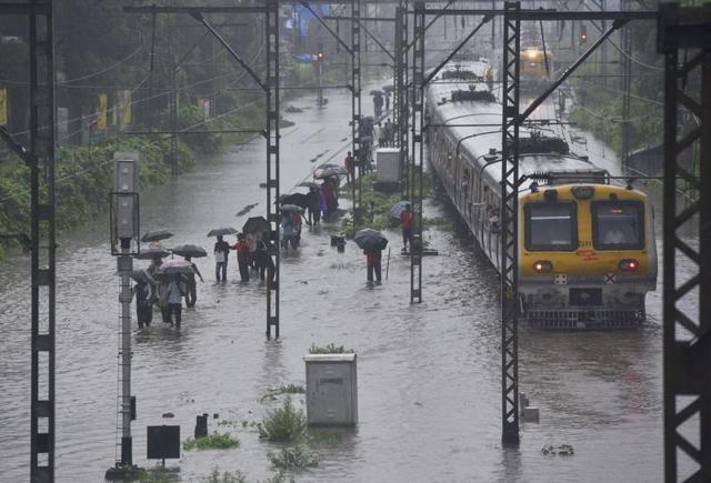 People wade through water logged  tracks as local trains stopped near Sion station after heavy rains in Mumbai on Friday. (Vijayanand Gupta/HT PHOTO) 