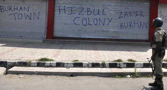 A paramilitary soldier watches graffiti mentioning slain Hizbul commander Burhan Wani in downtown Srinagar during a curfew on Friday. (Waseem Andrabi/ HT Photo)