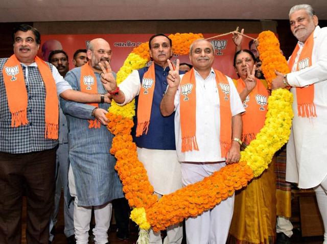 Newly elected Gujarat CM Vijay Rupani (in a blue jacket) and deputy CM Nitin Patel (third from right) garlanded by BJP president Amit Shah (second from left), Union minister Nitin Gadkari (extreme left) and Purushottam Rupala after a meeting at Gujarat BJP headquarters 'Kamlam' at Gandhinagar on Friday.(PTI)