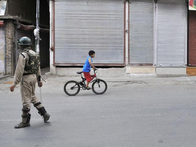 A Kashmiri boy rides a bicycle past a soldier in a deserted Srinagar street on July 19. (Waseem Andrabi /HT Photo) A Kashmiri boy rides a bicycle past a soldier in a deserted Srinagar street on July 19. (Waseem Andrabi /HT Photo)