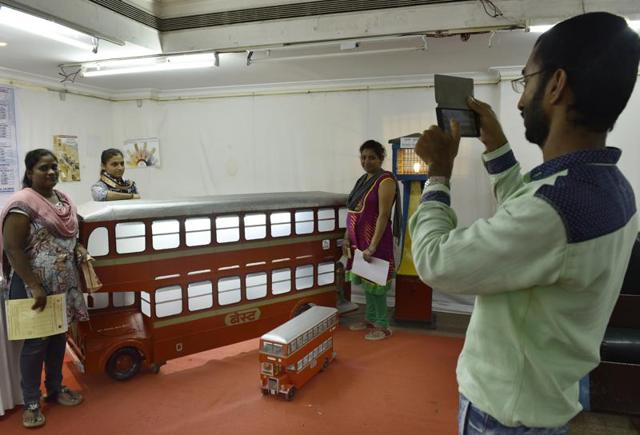 Visitors pose for a photograph next to a BEST bus model.  (ANSHUMAN POYREKAR) 