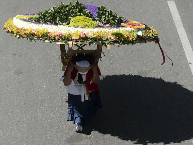 A woman carries a flower arrangement during the parade. (AFP) A woman carries a flower arrangement during the parade. (AFP)