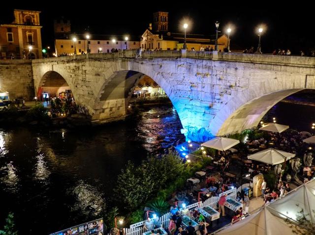 People walk on the river banks on Tiber Island during the Roman Summer event. (AFP) People walk on the river banks on Tiber Island during the Roman Summer event. (AFP)