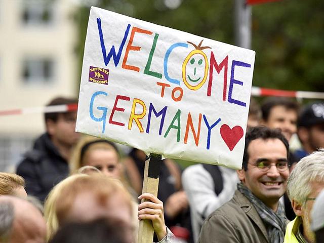 Germans welcome refugees in Dortmund in September 2015. Germany let in nearly 1.1 million migrants and refugees last year, posing an enormous challenge for its overstretched bureaucracy.. (AP File Photo) Germans welcome refugees in Dortmund in September 2015. Germany let in nearly 1.1 million migrants and refugees last year, posing an enormous challenge for its overstretched bureaucracy.. (AP File Photo)