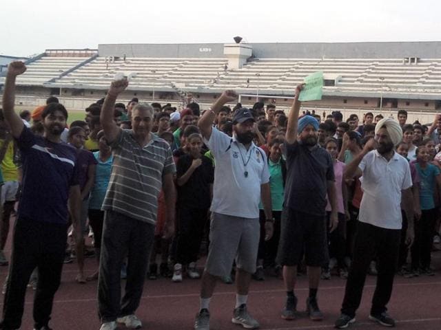 Sportspersons, coaches, parents, sports lovers and teachers protesting at Guru Nanak Dev Stadium on Tuesday evening in Ludhiana.(HT Photo)