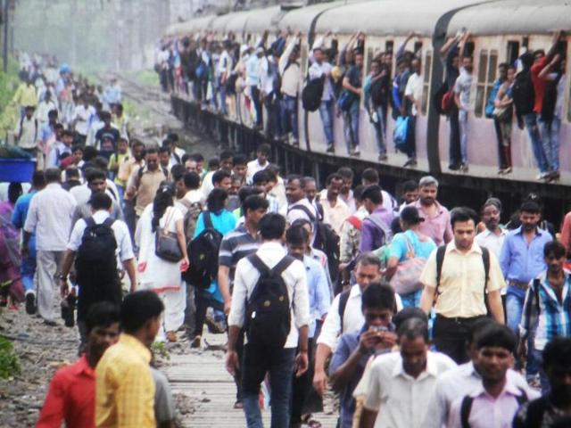 Passengers walk on the railway tracks in Thane as commuters from an overcrowded train look on (Praful Gangurde) Passengers walk on the railway tracks in Thane as commuters from an overcrowded train look on (Praful Gangurde)