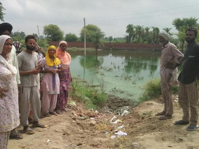 The residents of the Dalit colony standing near one of the sewage puddles at Thuhi village near Nabha.(HT Photo)