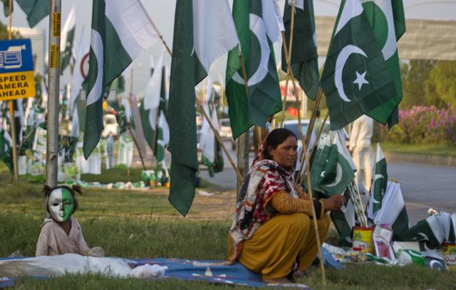 A vendor waits for customers with her daughter to sell national flags, badges and masks ahead of Pakistan’s Independence Day in Islamabad. (AP) A vendor waits for customers with her daughter to sell national flags, badges and masks ahead of Pakistan’s Independence Day in Islamabad. (AP)