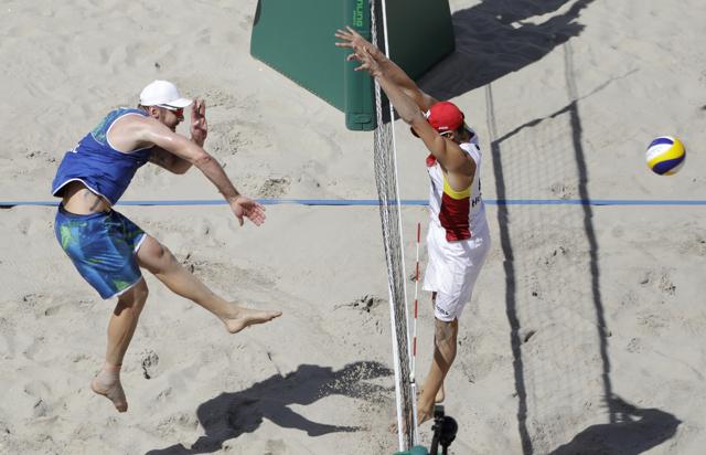 Brazil's Alison Cerutti (left) spikes against Spain's Pablo Herrera Allepuz during the men's beach volleyball round of 16 match at the 2016 Summer Olympics in Rio de Janeiro, Brazil, on Saturday. (Marcio Jose Sanchez/AP)