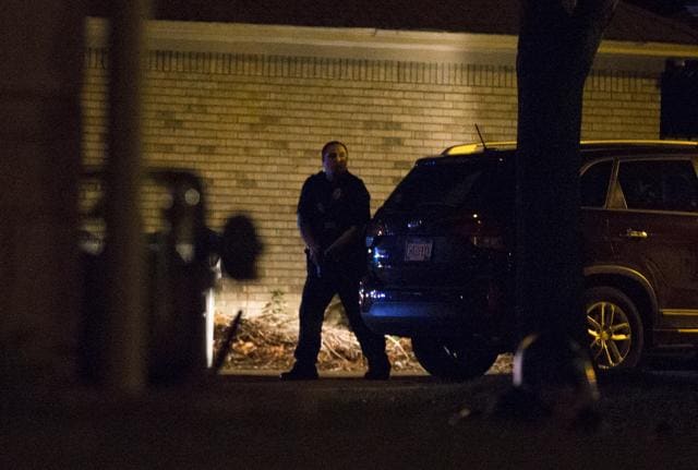 A police officer hides behind a car during the protests in Milwaukee. (AP)