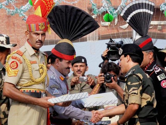 Pakistani Rangers sector Commander Shaukat Ali presents sweets to Border Security Force (BSF) Commandant Sudeep on the occasion of Pakistan's Independence Day at the Attari-Wagah border on Sunday.(PTI)