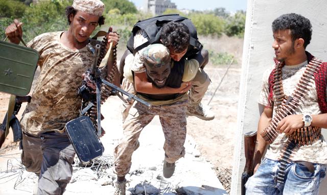 A fighter of Libyan forces while carrying a wounded colleague during a battle with IS fighters in Sirte on July 31. (REUTERS) A fighter of Libyan forces while carrying a wounded colleague during a battle with IS fighters in Sirte on July 31. (REUTERS)