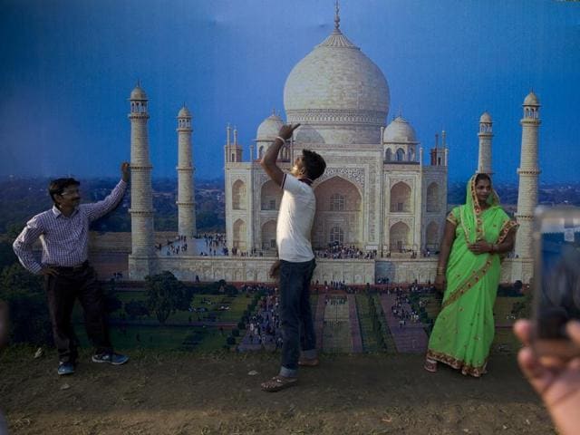 People get themselves photographed in front of a picture of the Taj Mahal. (AP Photo) 