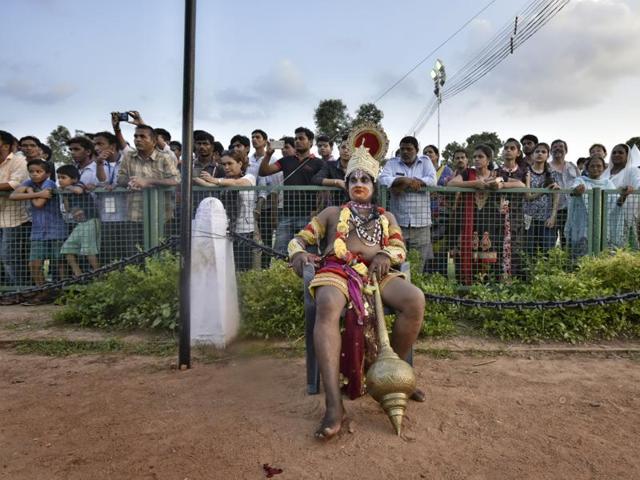 An artist dressed as Lord Hanuman takes a break, while onlookers click pictures, at the Bharat Parv in New Delhi. (Raj K Raj/HT Photo) 