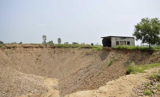 A Gujjar tribal family had to abandon this house when the plundering of earth brought it to an edge. This pit between Dhamian and Bariana villages of Hajipur sub-tehsil is more than 15 feet wide. Huge land has been usurped this way. (Ravi Kumar/HT Photo)