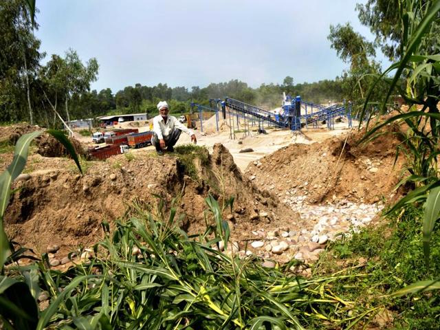 Kesar Singh sits over his devastated field that caved in with his standing maize crop last month at Kanjupeer village in Hajipur sub-tehsil of Hoshiarpur district. The farm is on the edge of an illegal quarry in the background, where a stone crusher operates.(Ravi Kumar/HT Photo)