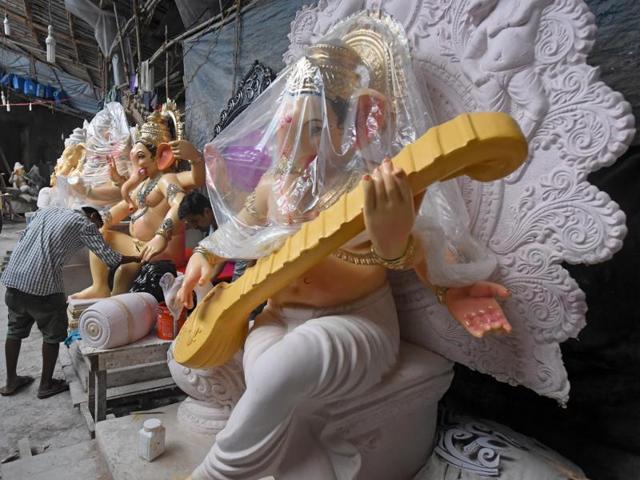 Under Cover: A Ganesha idol is covered with a plastic sheet as an artist devotes himself to monitor other idols at workshop in Mumbai n Tuesday. (Pratik Chorge) 