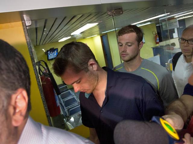Journalists surround American Olympic swimmers Gunnar Bentz, left, and Jack Conger, centre, as they leave the police station at Rio International airport. The two were taken off their flight from Brazil to the US on Wednesday by local authorities amid an investigation into a reported robbery targeting Ryan Lochte and his teammates. (AP Photo) Journalists surround American Olympic swimmers Gunnar Bentz, left, and Jack Conger, centre, as they leave the police station at Rio International airport. The two were taken off their flight from Brazil to the US on Wednesday by local authorities amid an investigation into a reported robbery targeting Ryan Lochte and his teammates. (AP Photo)