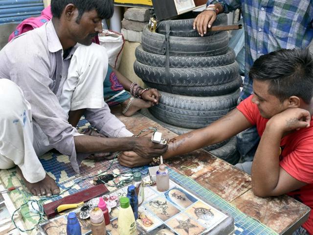 A man gets a tattoo on the roadside at the Rakhar Punia fair at Baba Bakala in Amritsar district on Thursday. (Gurpreet Singh/HT Photo)