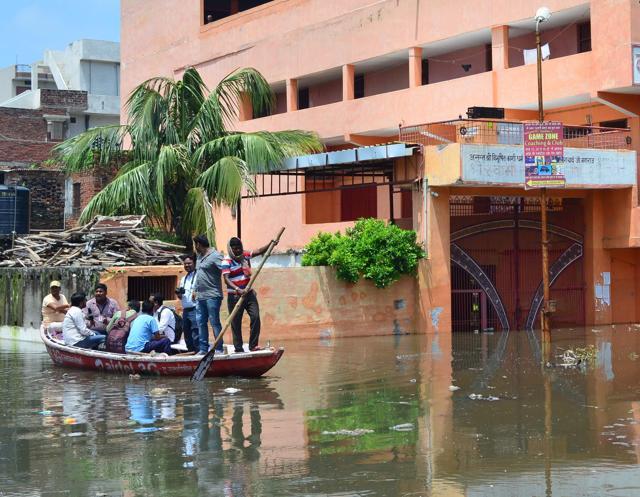 Residents use boats to leave the flooded Nagwa area in Varanasi on Saturday. (Adarsh Gupta/HT Photo)