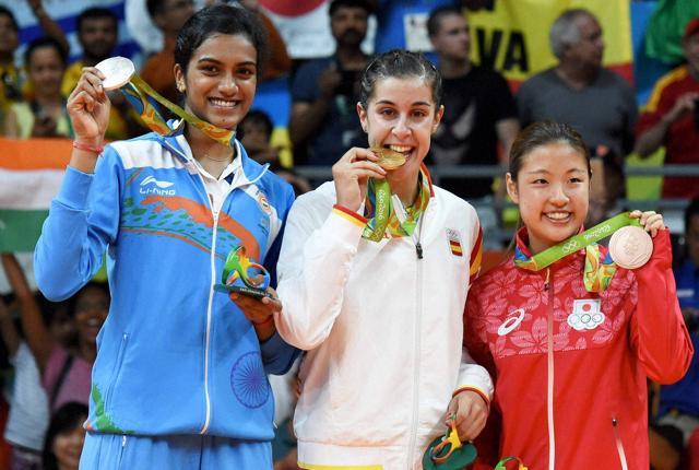(L-R) Silver medalist V. Sindhu Pusarla of India, gold medalist Carolina Marin of Spain and bronze medalist Nozomi Okuhara of Japan celebrate during the medal ceremony. (PTI Photo) (L-R) Silver medalist V. Sindhu Pusarla of India, gold medalist Carolina Marin of Spain and bronze medalist Nozomi Okuhara of Japan celebrate during the medal ceremony. (PTI Photo)