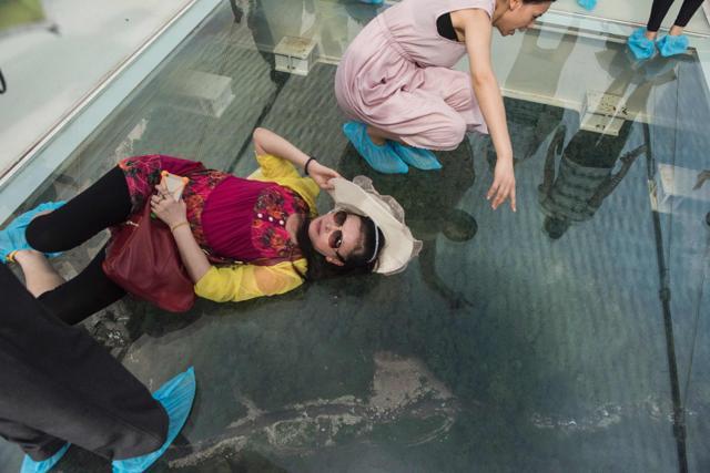 Tourists lie down on the glass-bottom bridge as a part of the experience of being on the world’s highest bridge. (AFP) Tourists lie down on the glass-bottom bridge as a part of the experience of being on the world’s highest bridge. (AFP)