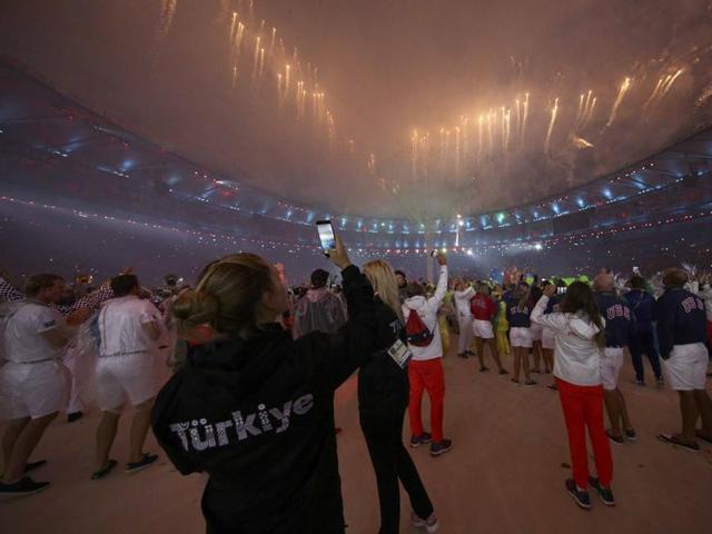 Athletes of various countries take photographs of the fireworks. (REUTERS)