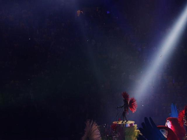 As the stadium goes dark, a single light illuminates a performer on a float. (REUTERS)
