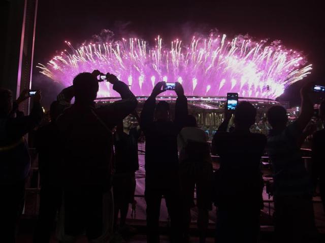 People watching from outside take photos of the fireworks display in the Maracanas stadium. (REUTERS)